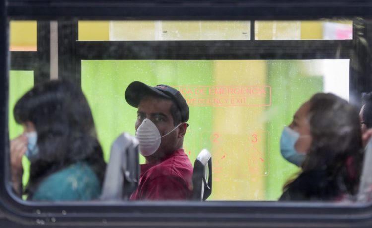Commuters wear masks Tuesday as they ride a bus in Mexico City. Mexico's government has broadened its shutdown of "non essential activities," and prohibited gatherings of more than 50 people but the federal call to stay home remains voluntary with no talk of penalties.