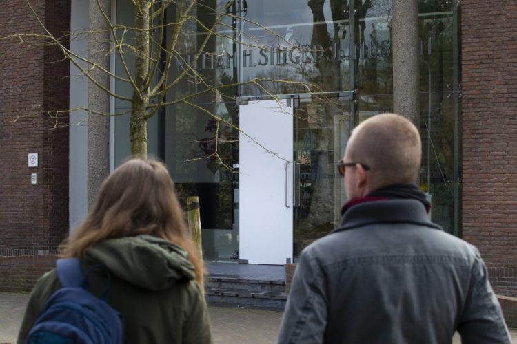 Two people look at the glass door that was smashed during a break-in at the Singer Museum in Laren, Netherlands, on Monday. The museum tis currently closed because of restrictions aimed at slowing the spread of the coronavirus.