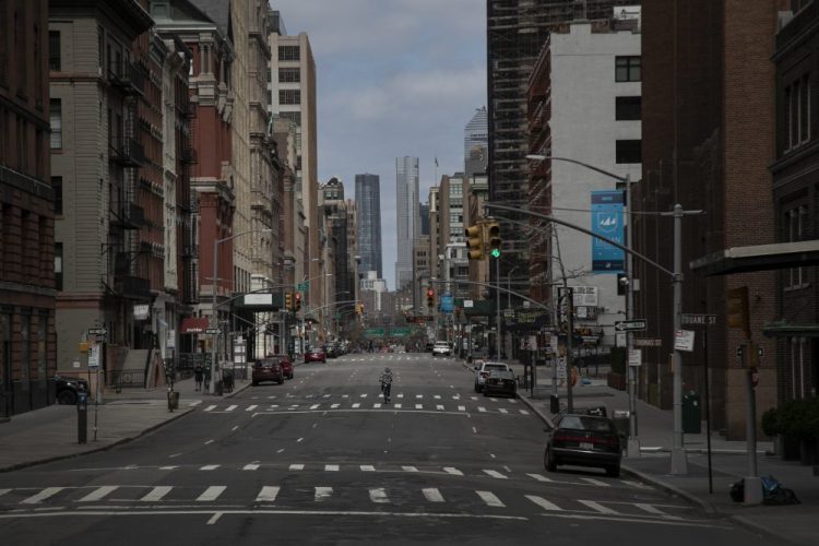 A cyclist rides down the middle of a main road in downtown New York on Sunday. New York City's mayor prepared Sunday to order his city to stay behind closed doors in an attempt to slow a pandemic that has swept across the globe. 
