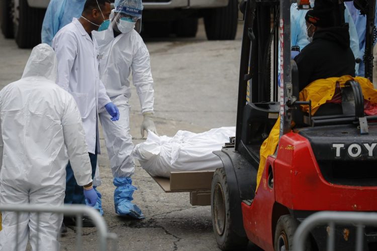 A body wrapped in plastic is prepared to be loaded onto a refrigerated container truck used as a temporary morgue by medical workers on Tuesday at Brooklyn Hospital Center in New York City.  