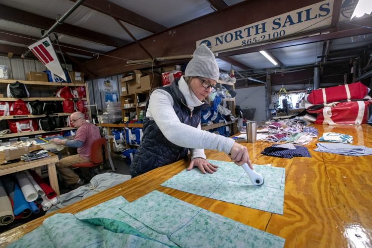 Karen Haley cuts cotton fabric for masks at the North Sails shop in Freeport.