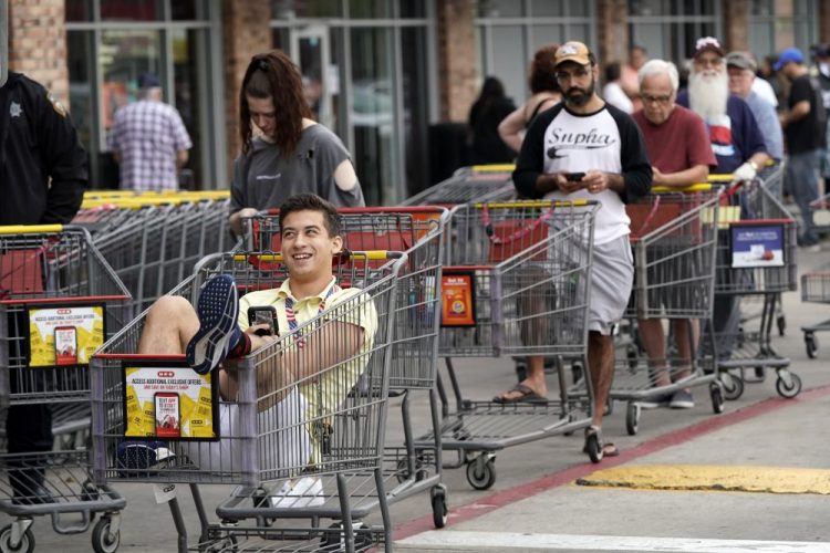 John Sinoski sits in a shopping cart while waiting for an H-E-B grocery store to open on Tuesday in Spring, Texas. Sinoski, who arrived around 6:30 in the morning, was near the front of a line of more than 150 people waiting to enter the store which opened at 8:00 a.m. 
