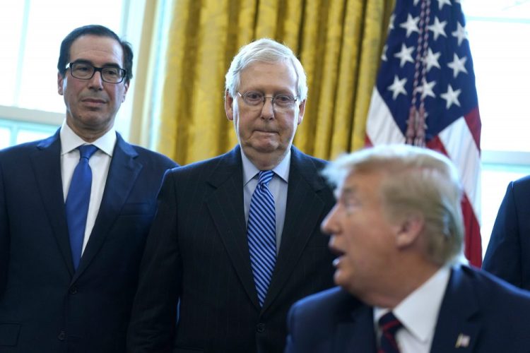 Treasury Secretary Steven Mnuchin and Senate Majority Leader Mitch McConnell, R-Ky., join President Trump  before he signs the coronavirus stimulus relief package in the Oval Office on March 27. McConnell said Republican Sen. Tom Cotton of Arkansas was among the first in Congress to raise an alarm about the virus.