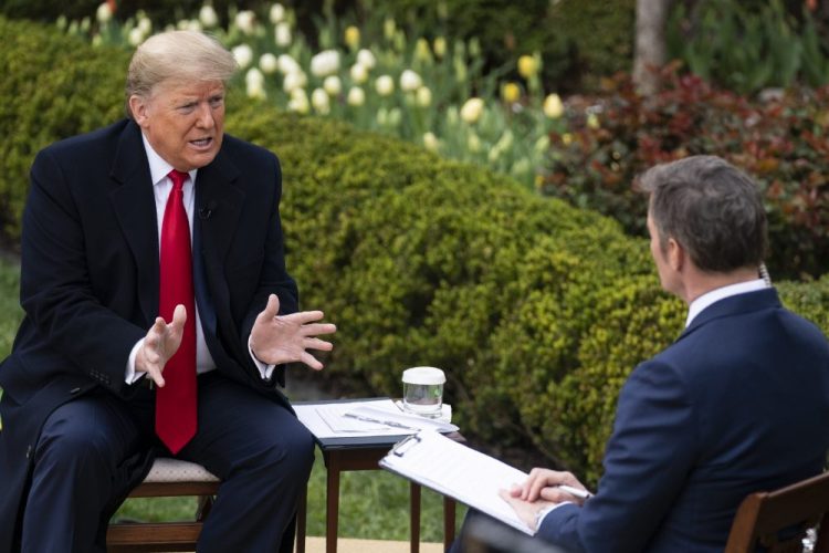President Trump talks with host Bill Hemmer during a Fox News virtual town hall with members of the coronavirus task force, in the Rose Garden at the White House on Tuesday. He said, “We have to go back to work, much sooner than people thought.”