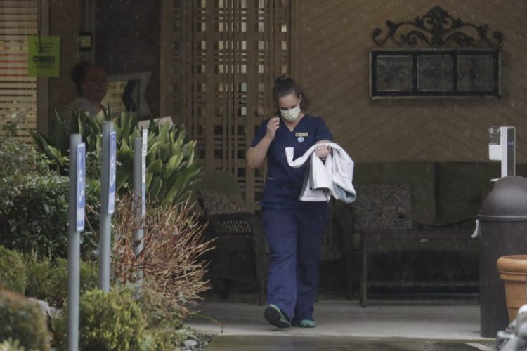 A worker at the Life Care Center in Kirkland, Wash., near Seattle, wears a mask as she leaves the building Monday. Several of the people who have died in Washington state from the COVID-19 coronavirus were tied to the long-term care facility, where dozens of residents were sick.