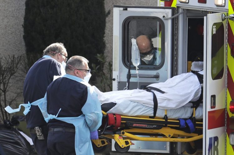 A person is loaded into an ambulance March 12 at the Life Care Center in Kirkland, Wash. The nursing home is at the center of the outbreak of the COVID-19 coronavirus in Washington state.
