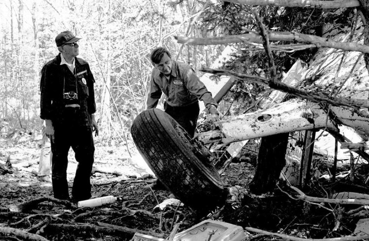 A National Transportation Safety Board team member, left, investigates the wreckage of Downeast Airlines Flight 46.
