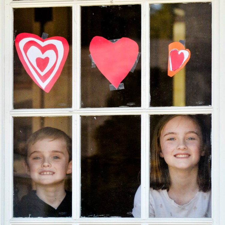 Callan Grant, 7, left, and Libby Grant, 11 stand for a portrait in front of the hearts they made on Saturday at their Augusta home.