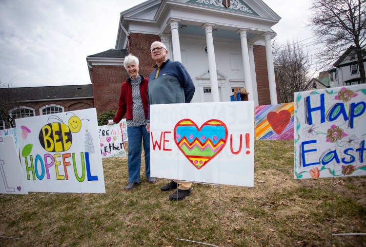 Volunteers Robin and Bill Carter will put out signs created by children on the front lawn of Woodfords Congregational Church on Saturday afternoon. The congregation will celebrate a sunrise service via Zoom on Easter morning.