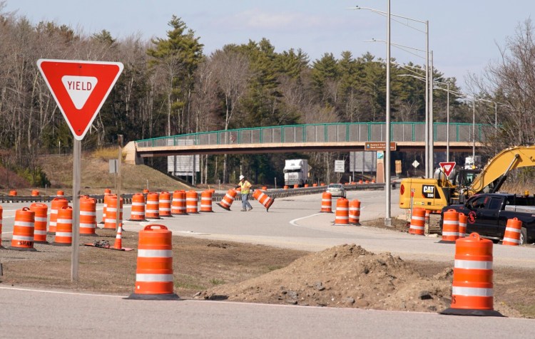 A construction worker with Shaw Brothers pulls barrier barrels across the on-ramp at the northbound Maine Turnpike service plaza in Kennebunk on Tuesday. Because of a sharp drop in traffic, road construction projects throughout the state are moving along faster than scheduled.
