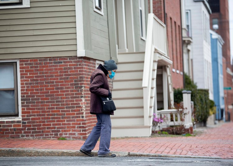 A masked woman walks on Brackett Street in Portland on Tuesday morning. 