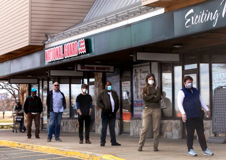 People wait in line six feet apart to go into Hannaford in Portland on Tuesday, April 7.