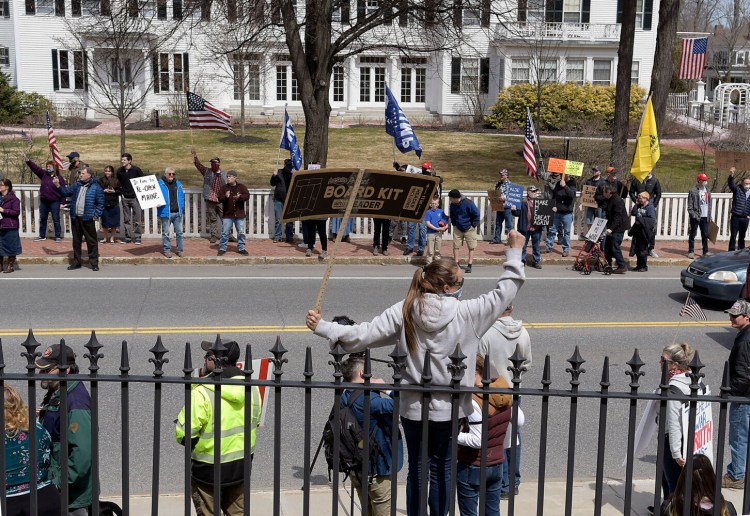 Protesters assemble Monday outside the State House Augusta, where hundreds of people gathered to call for coronavirus restrictions to be lifted. The governor's mansion, called the Blaine House, is seen in the background. 