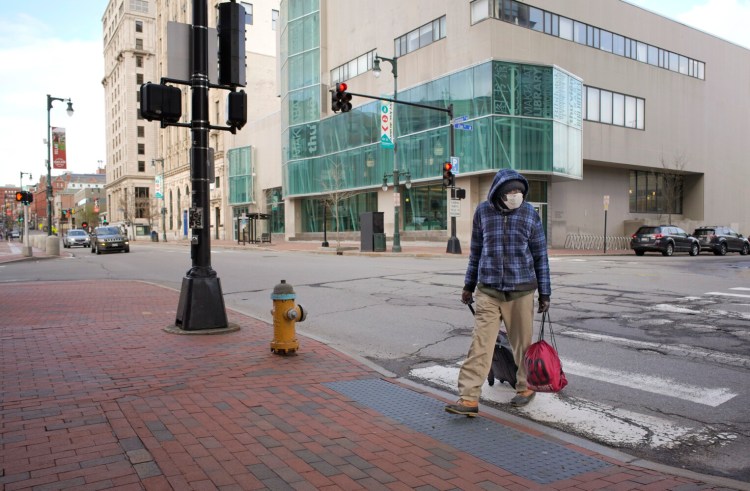A man crosses a nearly-deserted Congress Street in Portland on Wednesday.