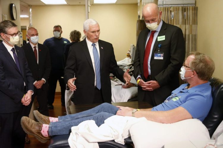 Vice President Mike Pence, center, visits Dennis Nelson, a patient who survived the coronavirus, during a tour of the Mayo Clinic on Tuesday in Rochester, Minn. Pence chose not to wear a face mask while touring the clinic. It's an apparent violation of the world-renowned medical center's policy requiring them.
