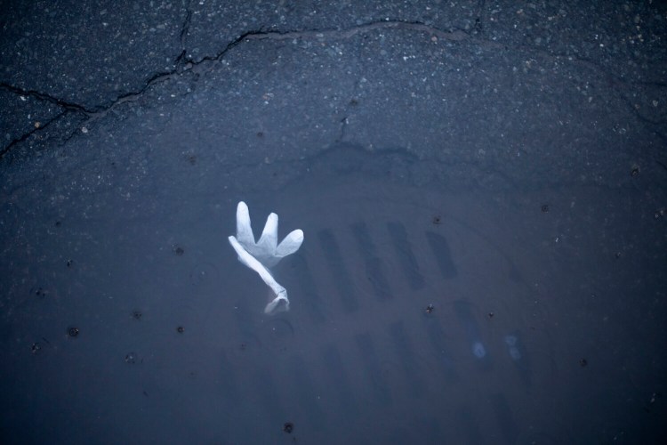 A medical glove rest in a puddle at a storm drain on Chadwick Street in Portland.