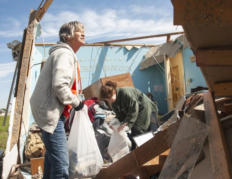 Stephanie Fatheree, right, salvages items from her house damaged from the tornado the previous night with help from a neighbor, on Thursday in Harrisburg, Ark. Fatheree said she took shelter with her mother, Angie, in the bathroom during the tornado. 