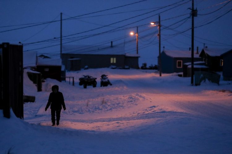 A woman walks before dawn in Toksook Bay, Alaska, a mostly Yuip'ik village on the edge of the Bering Sea, in January. Native American leaders are raising questions about how $8 billion in federal coronavirus relief tagged for tribes will be distributed, with some arguing that for-profit Alaska Native corporations shouldn't get a share of the funding.