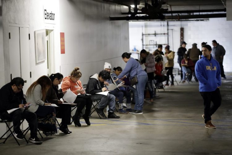 Unionized hospitality workers wait in line in a basement garage to apply for unemployment benefits  in Los Angeles in March.
