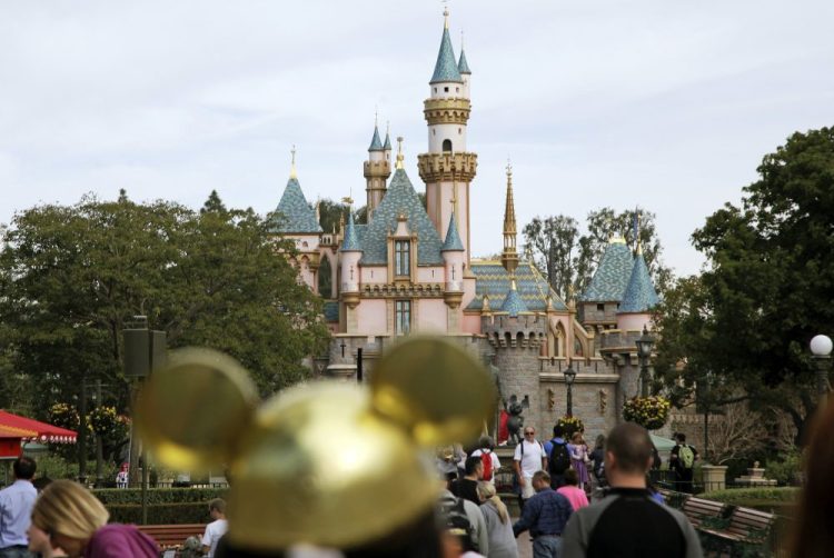 In this Jan. 22, 2015, file photo, visitors walk toward Sleeping Beauty's Castle in the background at Disneyland Resort in Anaheim, Calif.  