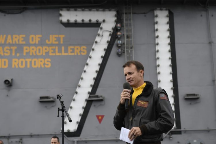 Navy Capt. Brett Crozier, commanding officer of the aircraft carrier USS Theodore Roosevelt, addresses the crew on the ship's flight deck on Nov. 15. U.S. defense leaders are backing the Navy's decision to fire the captain, who sought help for his coronavirus-stricken aircraft carrier. Videos showing his sailors cheering him as he walked off the vessel went viral on social media.