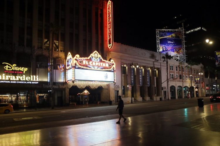 A man walks past El Capitan Theatre along the mostly empty Hollywood Boulevard on Thursday, April 2, 2020, in Los Angeles. 