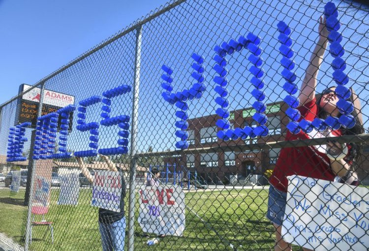 Adams Elementary School third-grade teacher Lisel Corneil, left, and fifth-grade teacher Allie Campbell are among educators who constructed from plastic drinking cups a "We Miss You All-Stars" message to their students in a fence in Spokane, Wash. 
