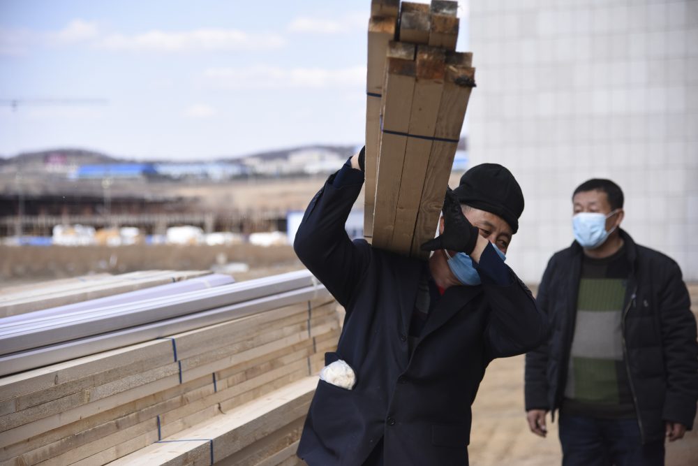 Laborers haul supplies to an office building being converted into a temporary hospital in Suifenhe in northeastern China's Heilongjiang Province on Friday. China is facing a new coronavirus flare-up along its remote northern border with Russia, far from the epicenter of Wuhan. 