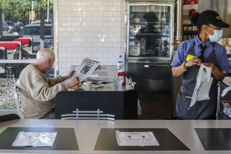 A Waffle House employee gets to-go orders ready as a seated guest eats his meal on April 27 in Brookhaven, Ga. Restaurants around metro Atlanta began to reopen dining rooms as restrictions were lifted. 