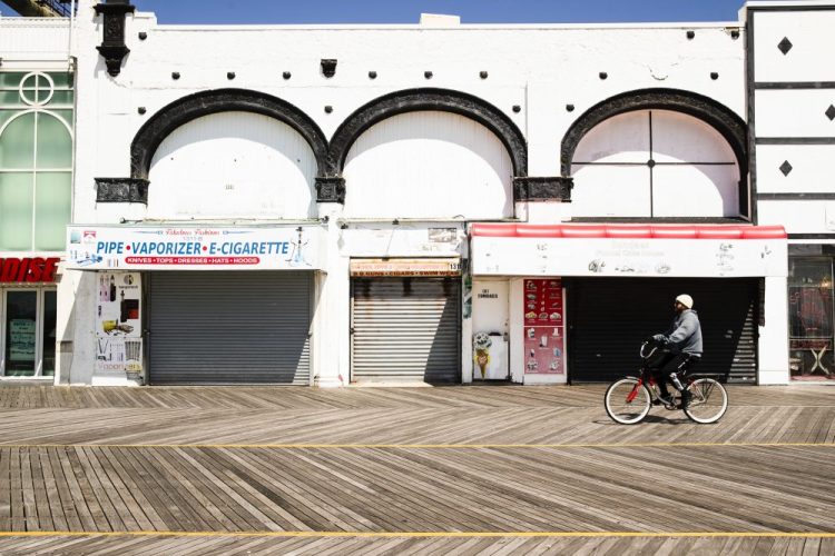 A cyclist rides past closed businesses on the boardwalk in Atlantic City, N.J., on Tuesday, April 28.