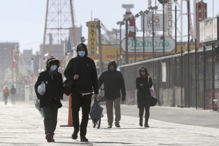 Pedestrians enjoy the warm weather on the boardwalk at Coney Island in New York, Sunday, April 12. Amid some signs of hope that the coronavirus infection rate is plateauing, New York is still wrapping up its worst week in deaths so far since the outbreak began. 