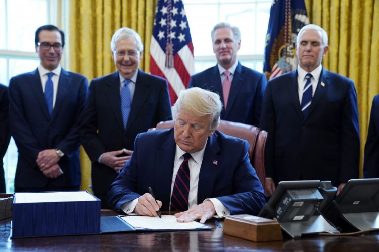 President Trump frequently appears with groups of people and never wears a face covering, but all who meet with him are required to undergo on-site rapid tests developed by Abbott Laboratories, which provide results within 15 minutes. Here, he signs the coronavirus stimulus relief package at the White House in March. From left, Treasury Secretary Steven Mnuchin, Senate Majority Leader Mitch McConnell of Ky., House Minority Kevin McCarthy of Calif., and Vice President Mike Pence, stand behind him.  