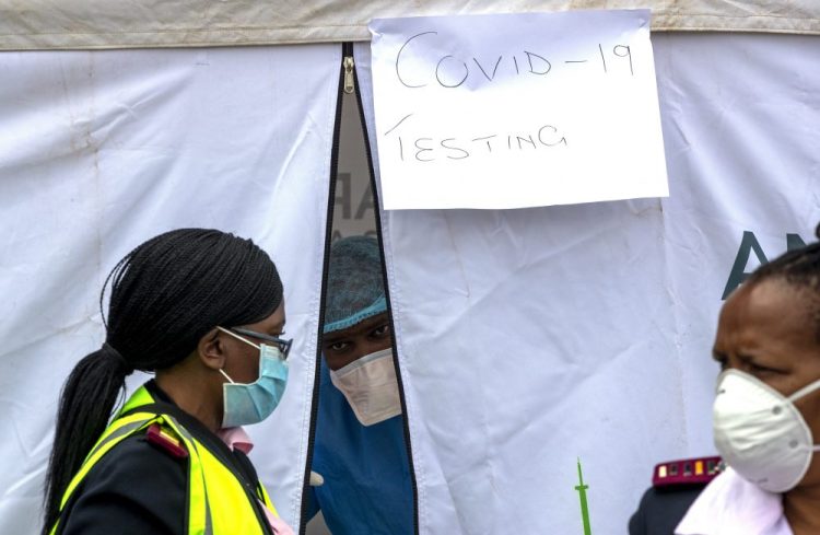 A health worker wears personal protective gear inside a testing tent while colleagues walk by outside during the screening and testing for COVID-19, in Lenasia, south of Johannesburg, South Africa, on Wednesday. South Africa and more than half of Africa's 54 countries have imposed lockdowns, curfews, travel bans or other restrictions to try to contain the spread of COVID-19. 