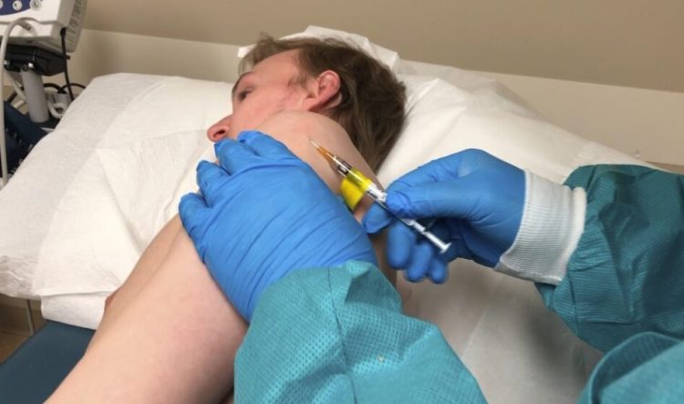 A participant in a COVID-19 vaccine trial receives an injection in Kansas City, Mo., on Wednesday. This early safety study, referred to as a Phase 1 trial, is using a vaccine candidate developed by Inovio Pharmaceuticals.