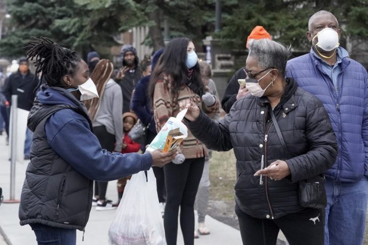 A worker hands out disinfectant wipes and pens as voters line up outside Riverside High School for Wisconsin's primary election Tuesday in Milwaukee. 