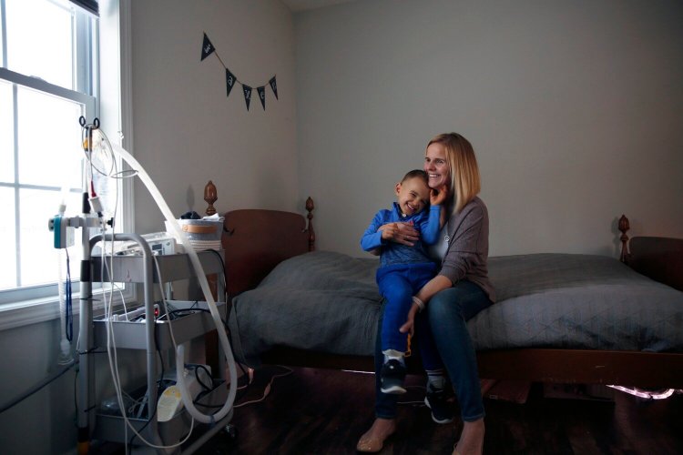 Cassie Steimlosk with her 4-year-old son, Jaxen, in his room at their North Yarmouth home. Most of his medical equipment and supplies are hidden in a closet, but the movable cart holds a breathing device and heart monitor. 