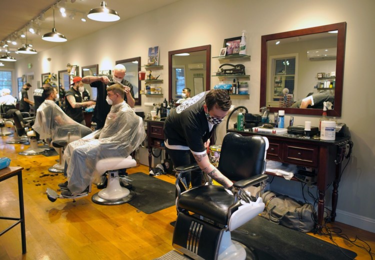 Garrison Guay sanitizes his barber chair in between customers at the Main Street Barber Shop in Kennebunk, which reopened Friday morning. The shop took customers by appointment only, under guidelines issued by the state. The barbers were booked for the whole day.