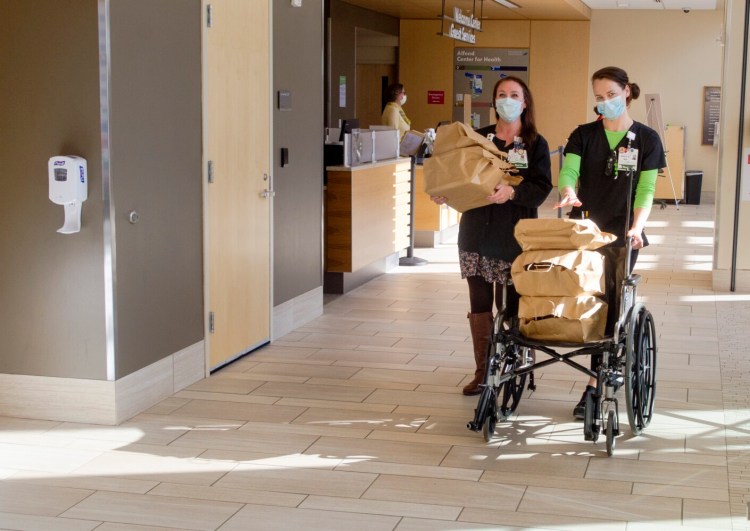 Nurses Danielle Easler, left and Emily Knox take dinners that were bought from the Quarry Tap Room with donations to a GoFundMe campaign to 1 West floor Thursday at MaineGeneral in Augusta.