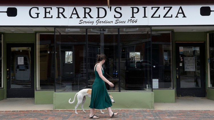 Kelly Flanagan walks past Gerard's Pizza on Water Street in Gardiner Sunday. A sign on the door said the sandwich shop plans to re-open on Tuesday.