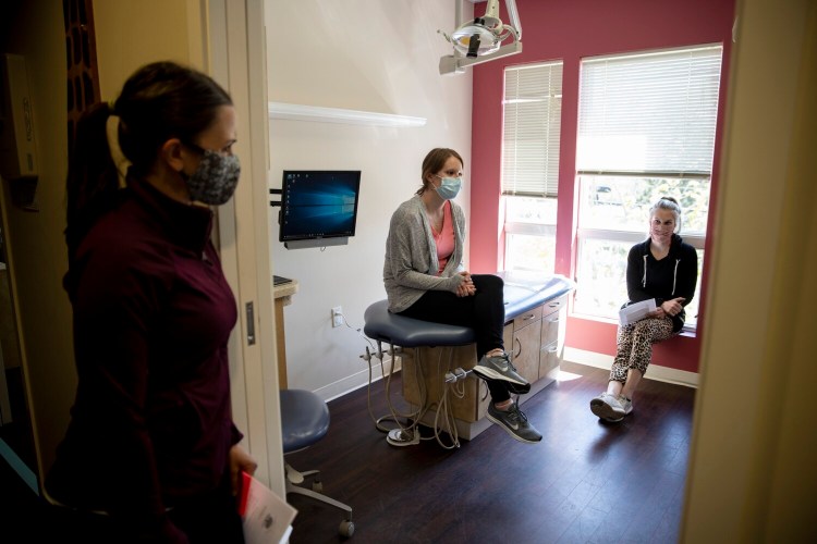 Dental hygienists, from left, Allyson Semle, Brittani Roussel and Mikaela Wiley meet Monday to discuss the reopening of their office, Southern Maine Pediatric Dentistry in Portland. The office will officially open Tuesday and the staff spent Monday preparing it for patients.