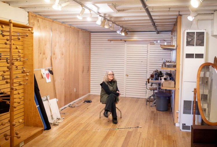Nancy Lawrence sits in her nearly empty store, Portmanteau, on Wharf Street in the Old Port on Wednesday. Lawrence is closing her shop after over 40 years of selling clothing and accessories, in part because of her fears about the coronavirus.