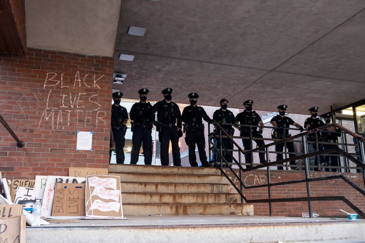 Portland police stand at the top of stairs as protestors disperse outside of the Portland police station on Middle Street on May 31.