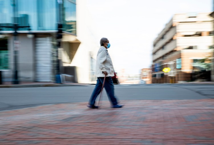 A woman walks on a largely deserted Congress Street in Portland on Monday morning.