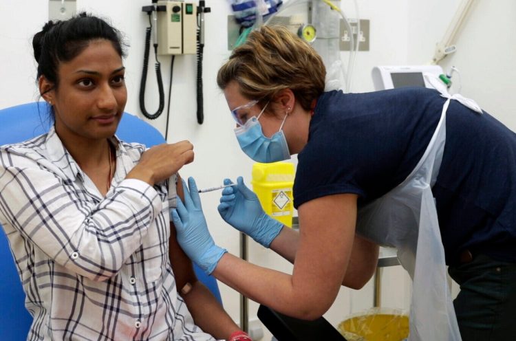 A volunteer is injected with either an experimental COVID-19 vaccine or a comparison shot as part of the first human trials in the U.K. to test a potential vaccine, led by Oxford University. About 100 research groups around the world are pursuing vaccines, with nearly a dozen in early stages of human trials or poised to start.