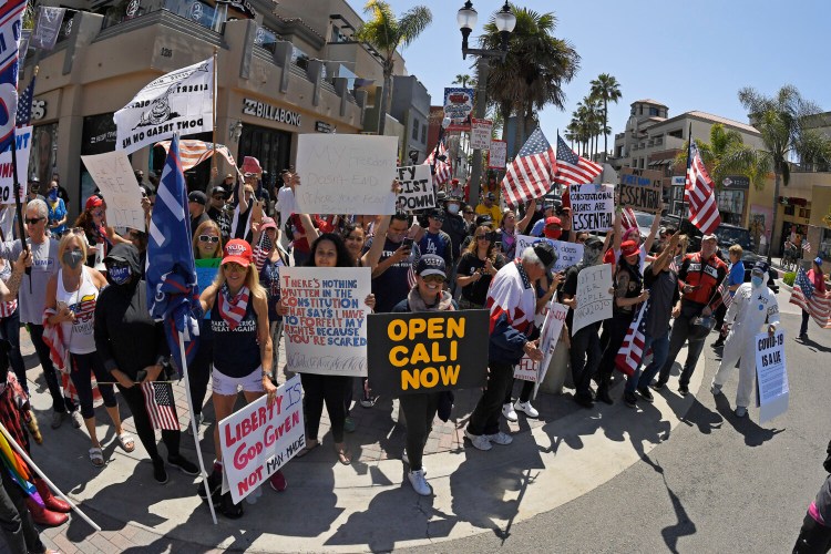 Protesters demonstrate against stay-at-home orders that were put in in Huntington Beach, Calif. Many African Americans watching protests calling for easing restrictions meant to slow the spread of the new virus see them as one more example of how their health and their rights just don’t seem to matter.