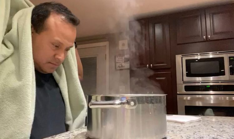 Alex Melo uses a steaming pot for a nebulizing treatment at his home in York, Maine. The retired Marine became critically ill with COVID-19 in April and spent a few days on a ventilator for pneumonia. He also developed blood clots that threatened his heart and lungs. 