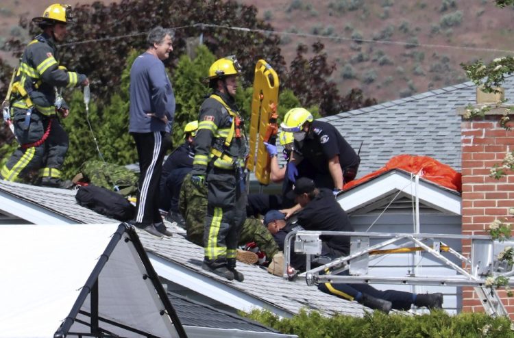 First responders attend to a person on a rooftop at the scene of a crash involving a Canadian Forces Snowbirds airplane in Kamloops, British Columbia, on Sunday. 