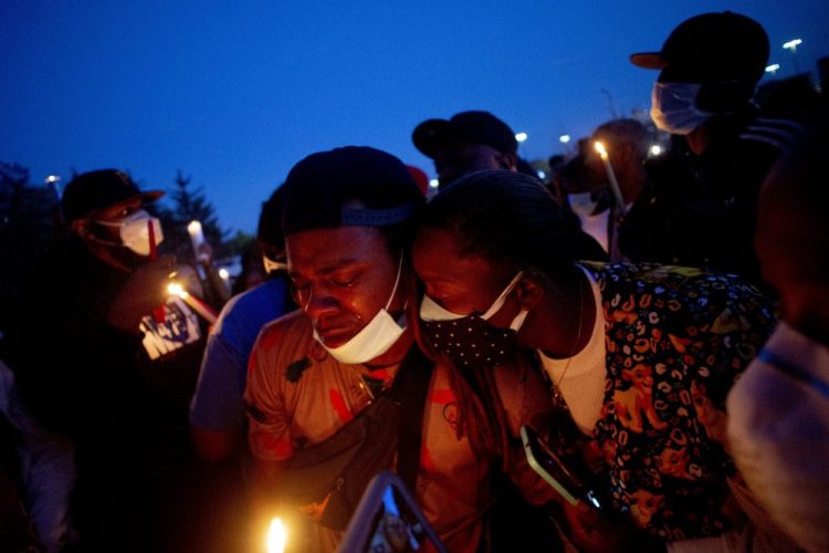 Maalik Mitchell, center left, sheds tears as he says goodbye to his father, Calvin Munerlyn, during a vigil Sunday in Flint, Mich. Munerlyn was shot and killed Friday at a Family Dollar store in Flint. He'd worked at the store as a security guard for a little more than a year.