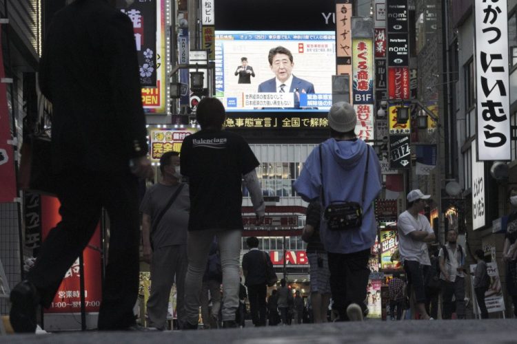 A public TV screen shows Japanese Prime Minister Shinzo Abe speaking at a press conference Monday in Tokyo. Abe announced the lifting of a coronavirus state of emergency in Tokyo and four other prefectures.