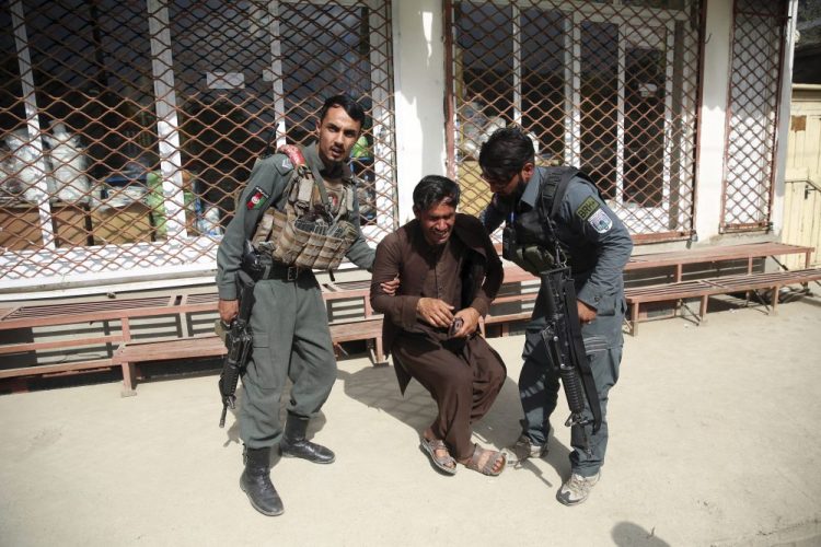 Afghan policemen comfort a man after an attack Tuesday on a maternity hospital in Kabul, Afghanistan. Militants stormed a maternity hospital, setting off an hours-long shootout with the police and killing over a dozen people, including two newborn babies. 